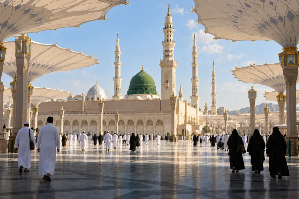 The Prophet's Mosque, Medina: the green dome, minarets and open white umbrellas over the courtyard, pilgrims in white and black seen from behind, bands of calligraphy, bright morning